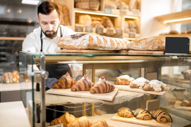 seller putting delicious croissants on the store showcase of the bakery house